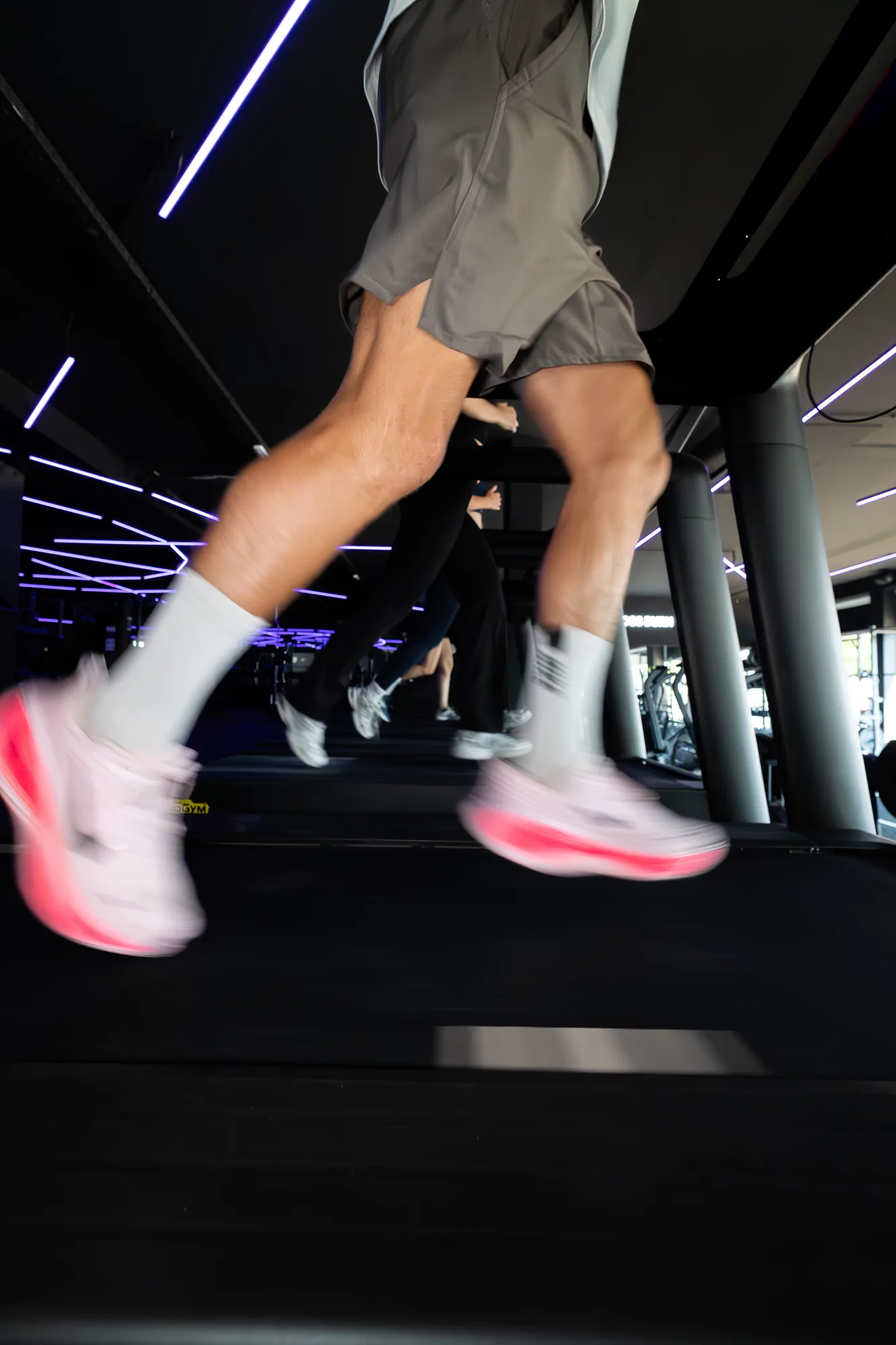 Runners in motion on treadmills under neon lighting at ONE PULS Brussels
